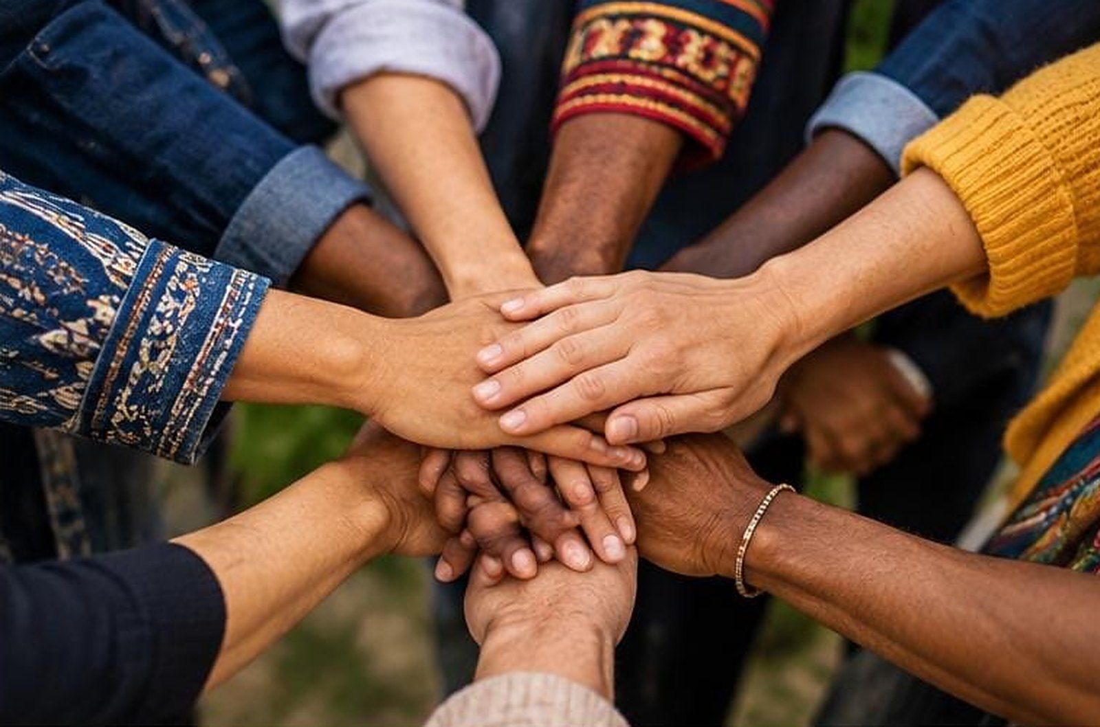 Manos de personas diversas unidas en el centro de un círculo